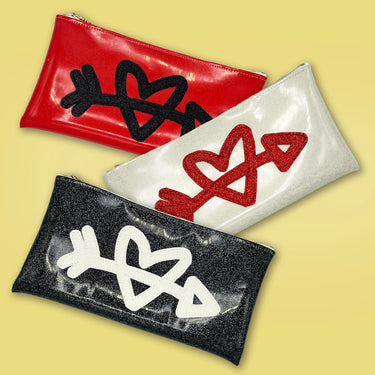 red, black and white heart and arrow clutches on a gold background